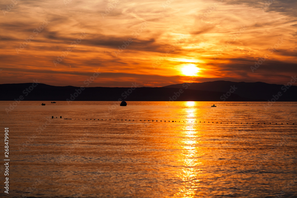 Fototapeta premium Orange sunset on the sea with the sun, a beautiful sky on the background of mountains