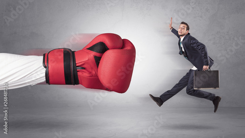 Businessman gets a hit from a giant hand with boxing gloves