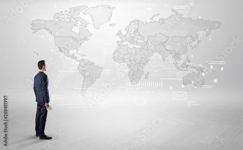 Businessman standing with his back and looking at a worldwide map with objects in his hand 