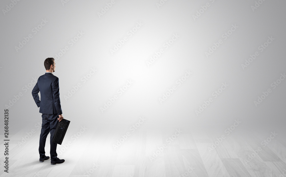 Man standing with his back in an empty room with object in his hand Man standing with his back in an empty room with object in his hand