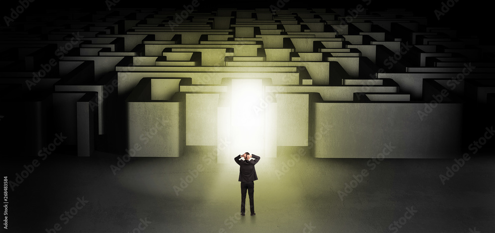 Lost businessman standing at the dark labyrinth with illuminated door
Lost businessman standing at the dark labyrinth with illuminated door