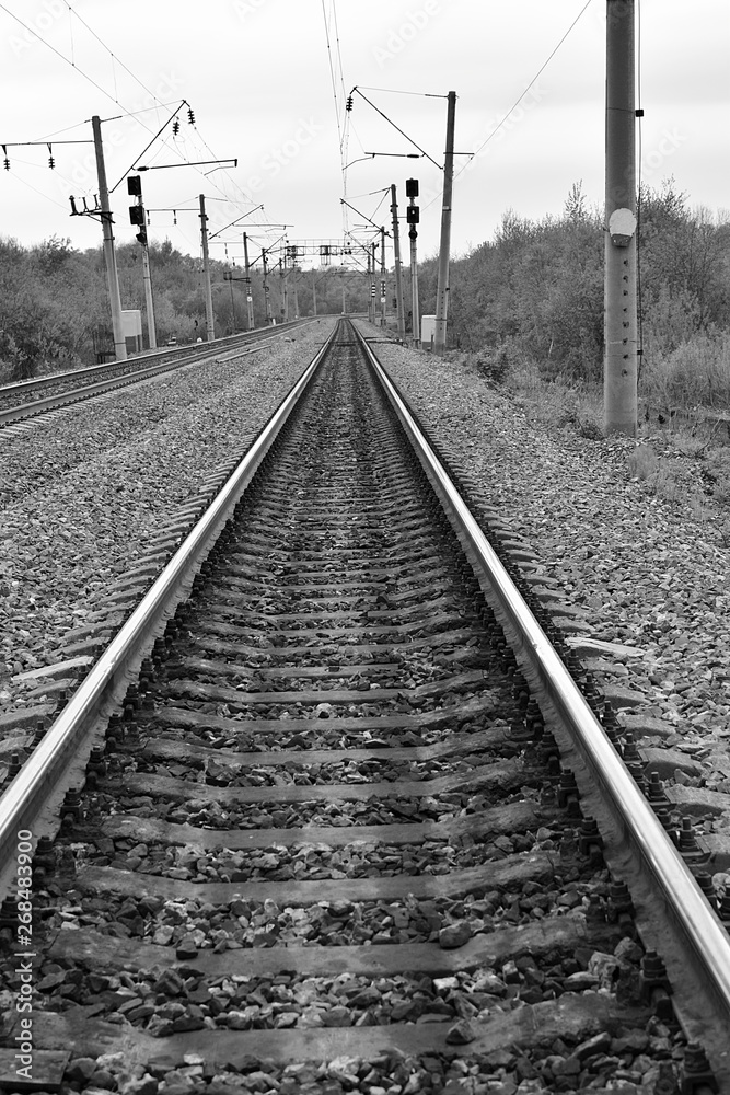Road for trains. Guide rail track. Vertical black and white photo.