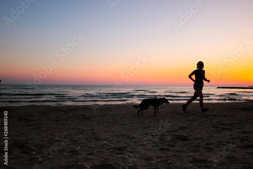 silhouette of running women on the beach at sunset