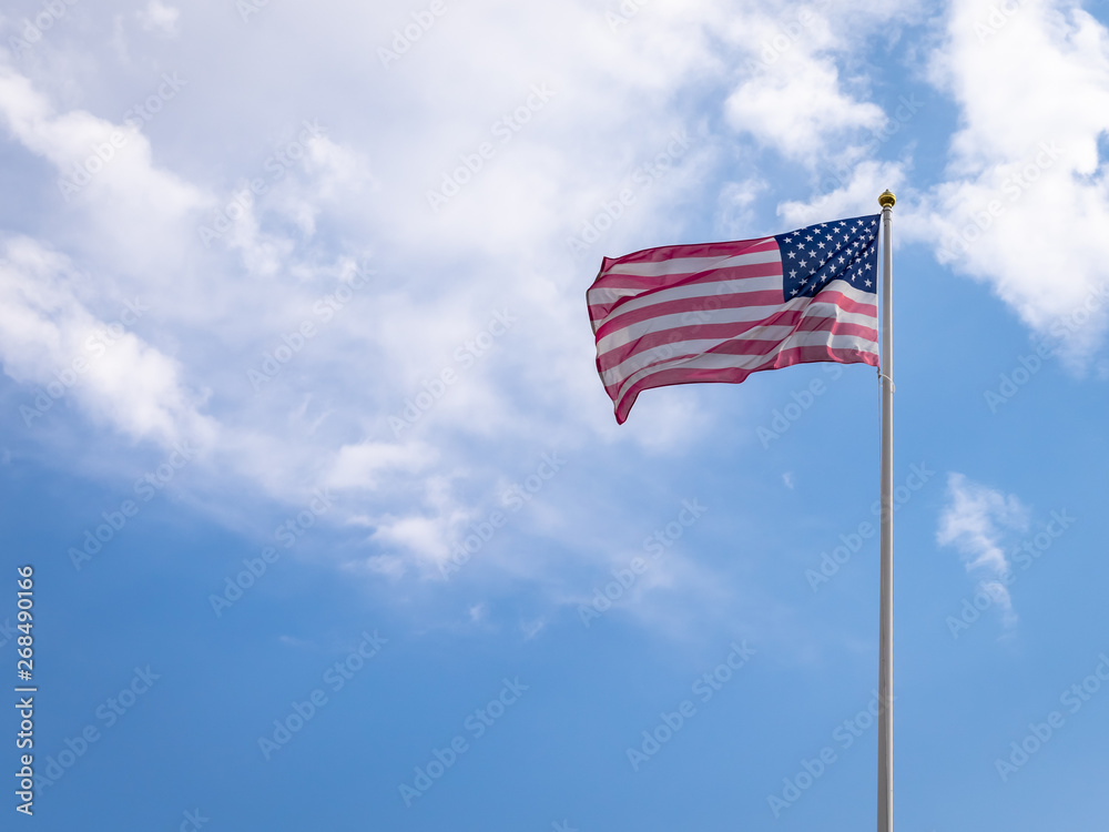 American Flag against Blue Sky with white clouds. American flag fluttering in wind. Independence Day USA. 