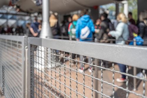 Queue in a park with a security fence