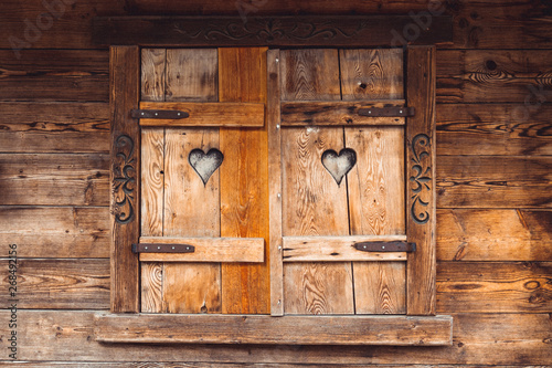 Old wooden windows of a wooden house with two cutouts of hearts