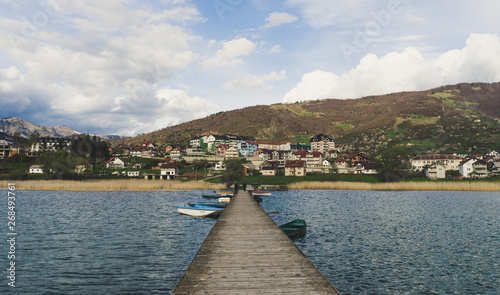 People in wood pier over Plav lake. Fisherman small coast town with ferryboats in Montenegro photo