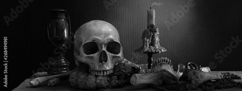 Valokuva Skull on rotten pumpkin with candle light and lantern on the plank and  pile of