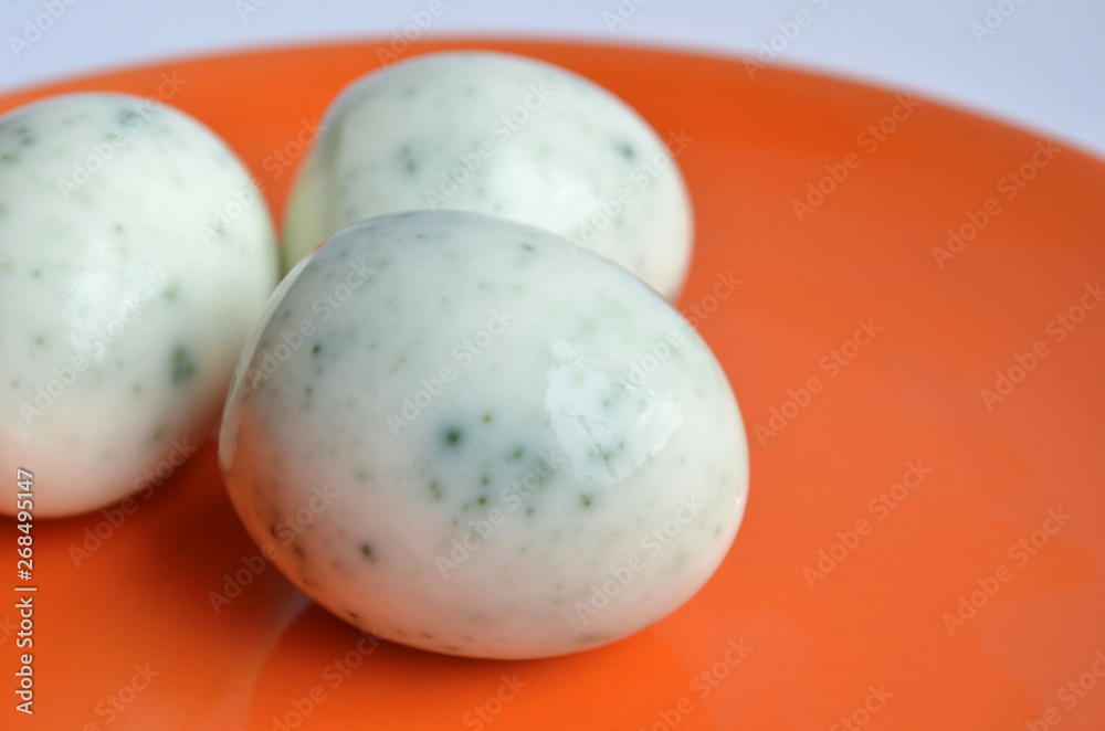 Three peeled eggs after painting in hibiscus tea, look like spoiled and covered with mold on orange plate macro Three peeled eggs after painting in hibiscus tea, look like spoiled and covered with mold on orange plate macro