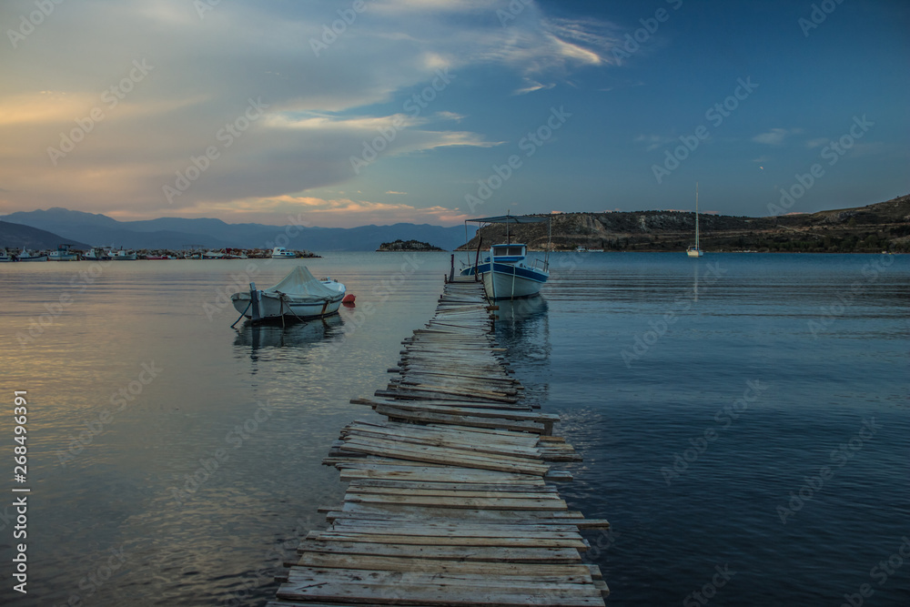 poor wooden pier in harbor Asian place with small fishing boats, evening blue twilight lighting time