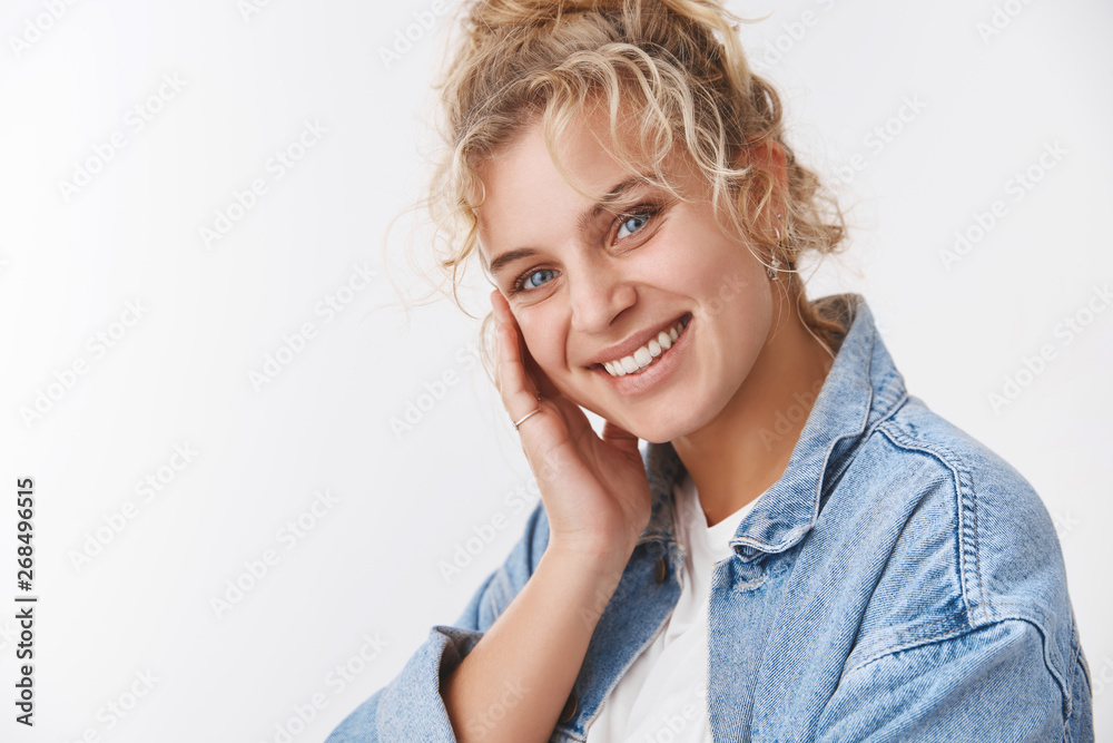Fototapeta premium Cosmetology, wellbeing concept. Attractive fair-haired european girl smiling blushing cute tilting head touching perfect clean skin like face after applying skincare product, smiling satisfied