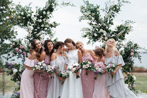 Beautiful elegant slim smiling bridesmaids in delicate pink beige summer dress on the wedding ceremony.