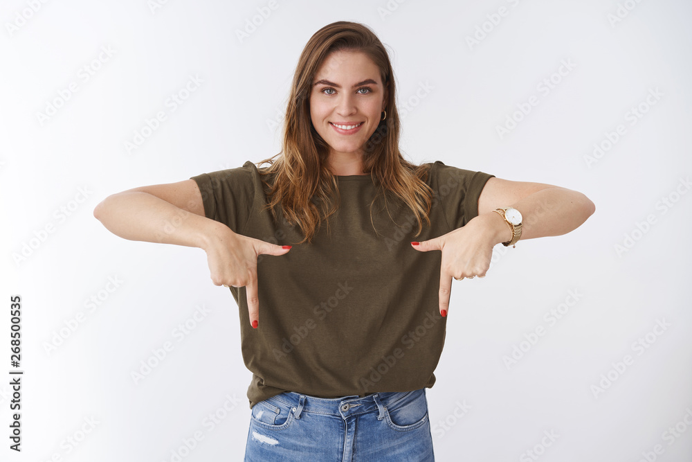 Studio shot attractive pleasant outgoing confident caucasian woman short hairstyle olive t-shirt pointing index fingers bottom down side smiling pleased showing promo recommending product Studio shot attractive pleasant outgoing confident caucasian woman short hairstyle olive t-shirt pointing index fingers bottom down side smiling pleased showing promo recommending product