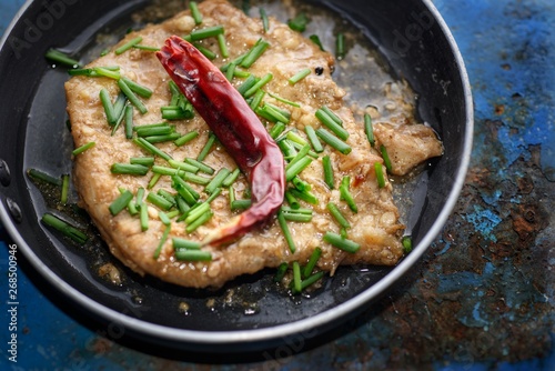 Deep Fried Pork Cooked with Garlic and pepper topped with dried chillies and spring onions on wooden table background