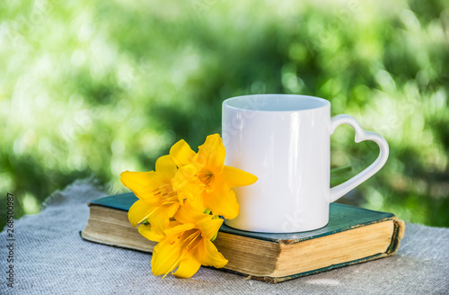 Cup of coffee and book. Cup of tea and flowers. White mug on natural background