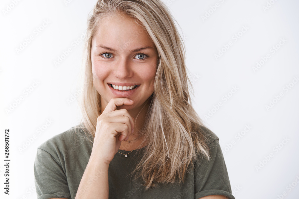 Close-up shot of attractive confident and positive european blonde with small tattoo touching chin assured smiling having creative interesting idea posing pleased and cheeky over white background Close-up shot of attractive confident and positive european blonde with small tattoo touching chin assured smiling having creative interesting idea posing pleased and cheeky over white background