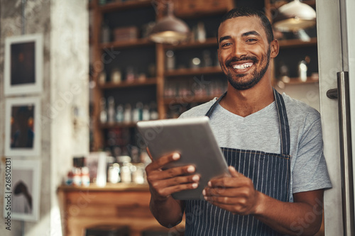 Smiling male cafe owner holding digital tablet in his hand