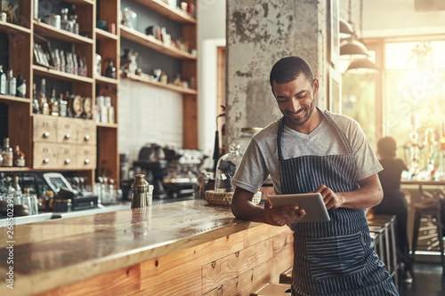 Happy male owner of cafe using digital tablet