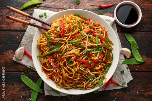 Chow mein, noodles and vegetables dish with wooden chopsticks photo