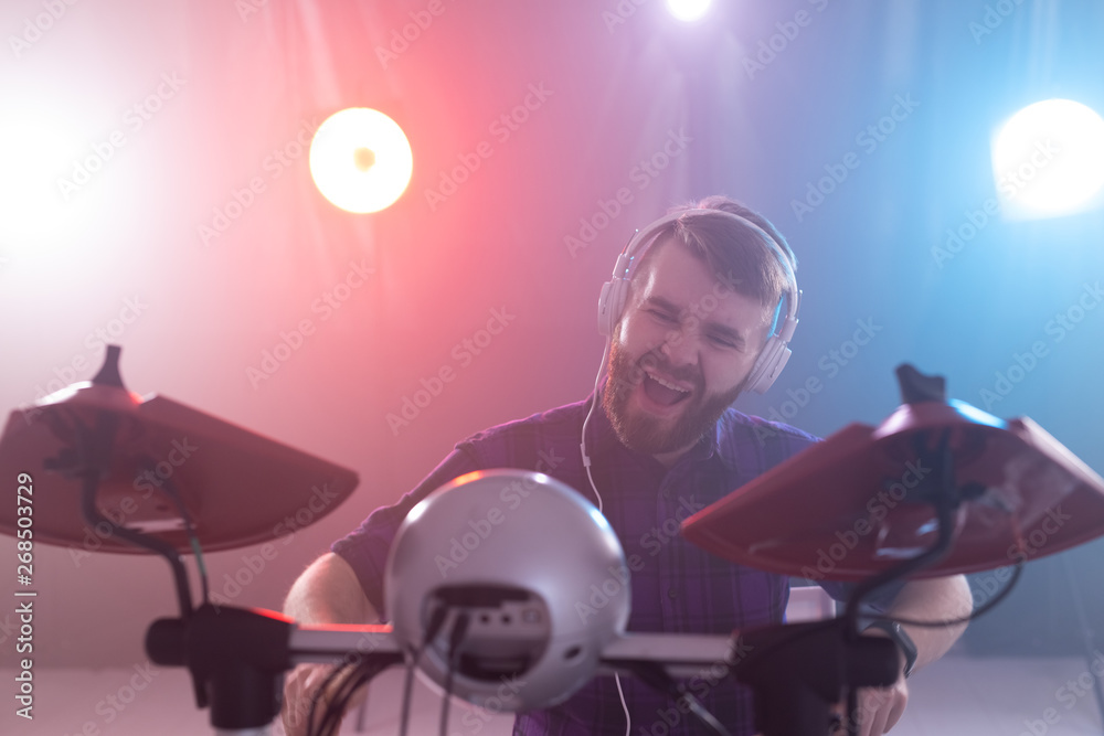 hobby, music and people concept - portrait of a man with white headphones playing drums, having fun