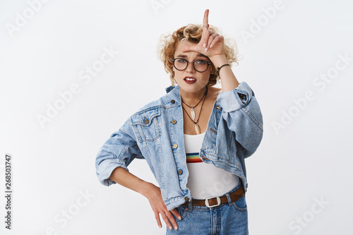 Girl looking with dismay at losers. Portrait of arrogant and confident good-looking stylish woman with short blond haircut mocking rival showing L letter on forehead and grimacing like snob photo