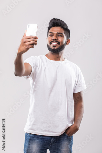 Photography Young handsome Indian man taking selfie with mobile phone isolated on white back
