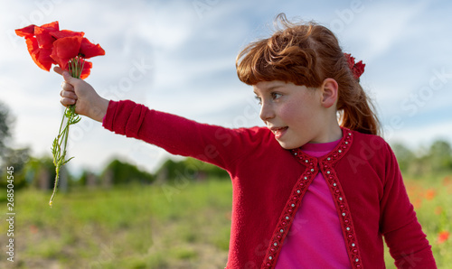 Bambina con capelli rossi che offre un mazzo di papaveri alla mamma in un campo di papaveri photo