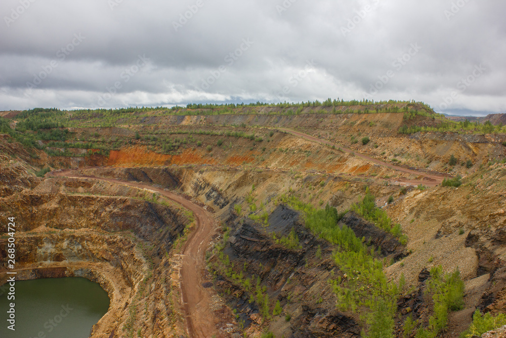 Obraz premium Odkrywkowa geologia kamieniołomu rudy żelaza z zieloną wodą