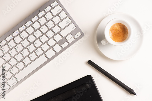 Graphic Designer white work table with computer and coffee.