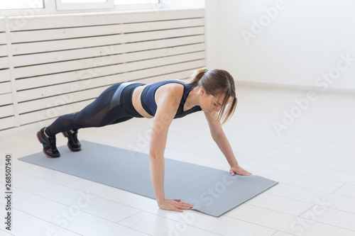 People, sport and fitness concept - young beautiful sportswoman doing push ups