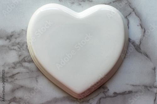 White glossy porcelain heart on a marble texture. Wedding card; A love note. Copy space