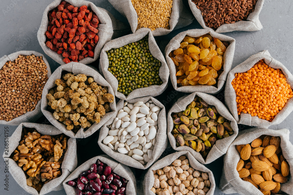 Top view of healthy dry ingredients in burlap bags. Nutritious cereals and dried fruit: almond, garbanzo, pistache, goji, buckwheat, mulberry, legume in cloth sacks