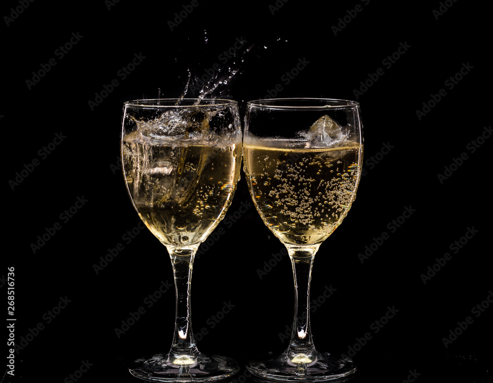 Two crystal wine glasses with a drink, falling ice and splashes
