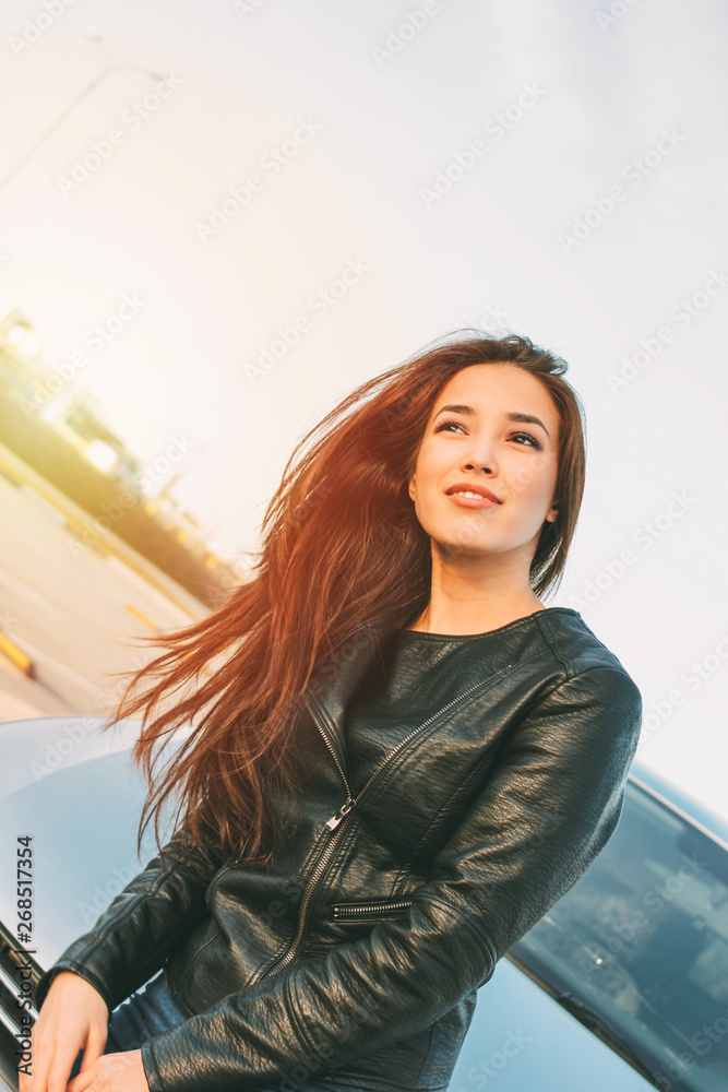 Fototapeta premium Beautiful charming brunette long hair young asian woman in black leather jacket near her car
