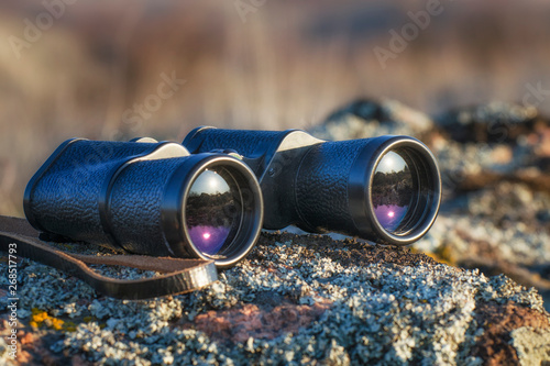 Black binoculars closeup on the rock. Morning time of day in the steppe. photo