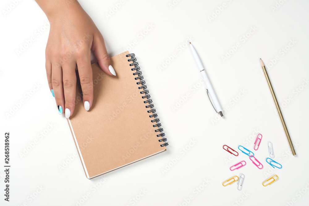 Female hand writing in a notebook at the desk. Top view, copy space. White table with planning book. Woman's hands with perfect manicure. Mockup for your design. Flat lay style. Female hand writing in a notebook at the desk. Top view, copy space. White table with planning book. Woman's hands with perfect manicure. Mockup for your design. Flat lay style.