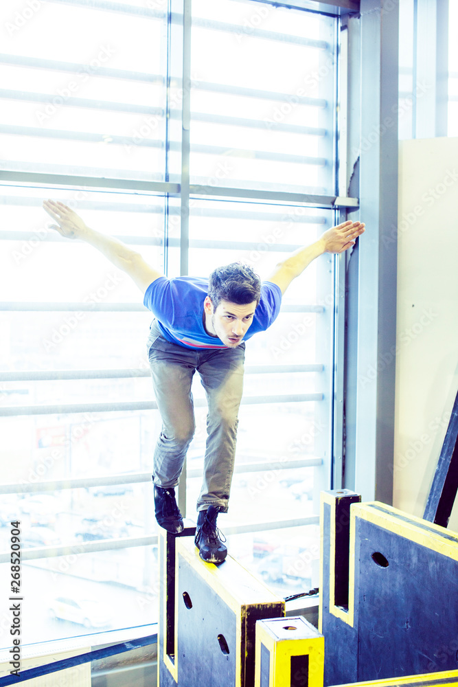 young handsome man doing parkour in gym inside, lifestyle sport people concept