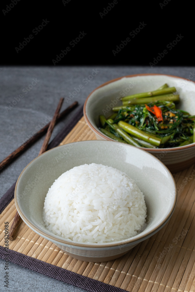 Fried morning glory with rice in gray bowl on table.