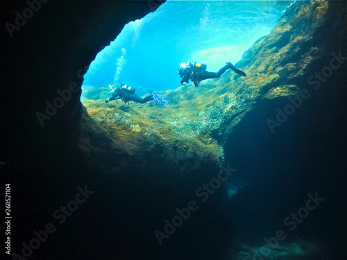Underwaterphoto of two scuba divers by entrance of cave. Taken off the coast of the island El Hierro, the smallest of the canary islands in Spain