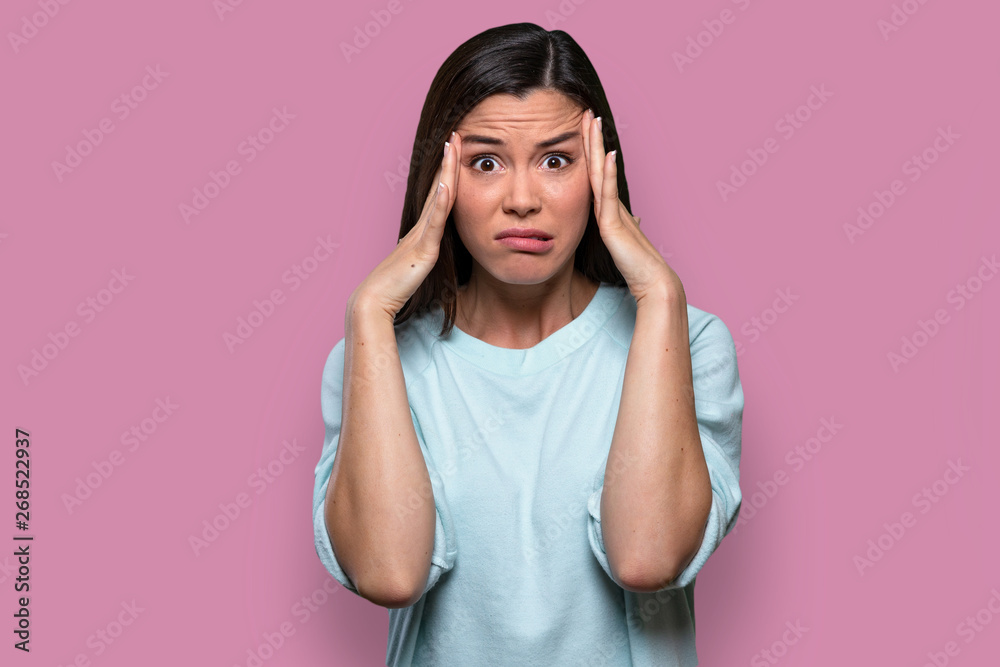 Isolated facial expression of a worried, concerned, fearful, regretful woman, expressing distress and inner conflict, pink background Isolated facial expression of a worried, concerned, fearful, regretful woman, expressing distress and inner conflict, pink background