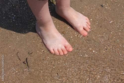 A baby try to step in to the sea water at the first time in a sunny day. With blurry sea background.
