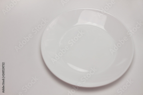 Empty round white plate isolated on white background. Top view, flat lay, copy space, mock up.