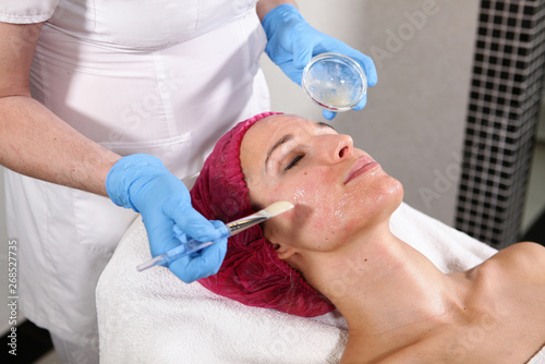 Close-up of the patient s face in the cosmetology office. Apply to the face means to moisturize and rejuvenate the skin. non-surgical facelift. Brush with the drug in the hands of a beautician.