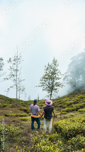 Senior couple traveller holding hands in a mountain tea field surrounded by mist in Sri Lanka