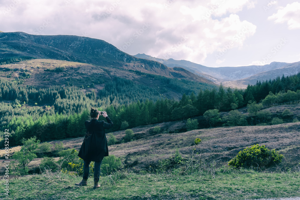 Young woman taking a picture of isle of Arran forest.