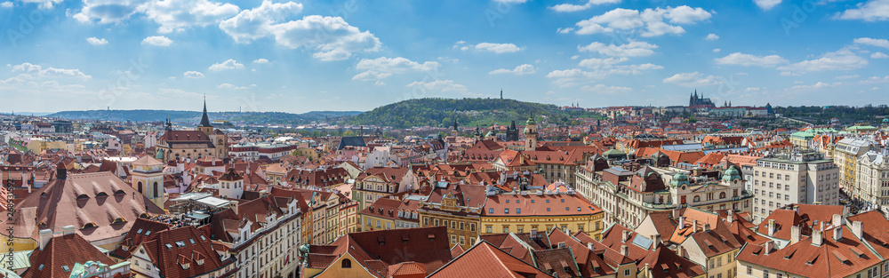 Outdoor sunny panoramic aerial top view of Prague old town cityscape, Charles Bridge tower and background range of mountain with Castle, St. Vitus Cathedral and Petrin tower in Prague, Czech Republic.