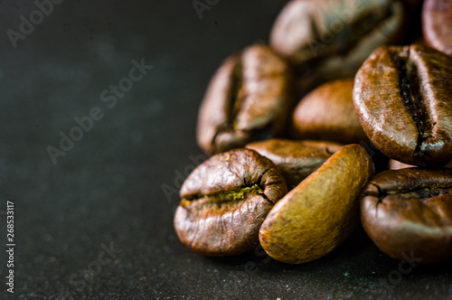 Brown roasted coffee beans on black background, close up, macro