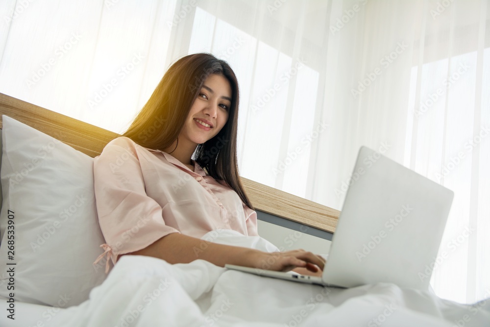 Portait of smiling lady in pink pajama wake up searching information in notebook on the bed Portait of smiling lady in pink pajama wake up searching information in notebook on the bed