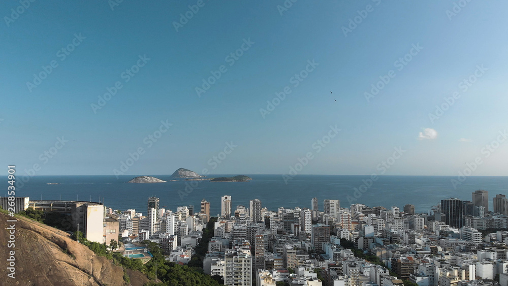 Aerial view of islands in front of the coast of the beach neighbourhood of Ipanema in Rio de Janeiro with urban residential area in the foreground with a blue sky
