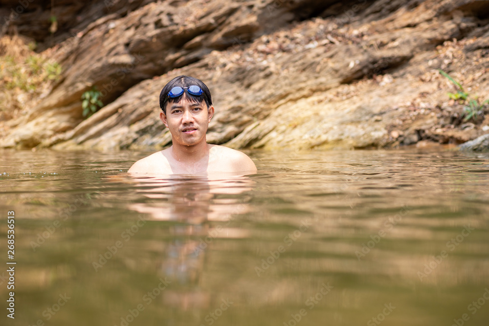 Asian man with goggles on head swimming in river, Handsome man enjoy swimming in water 